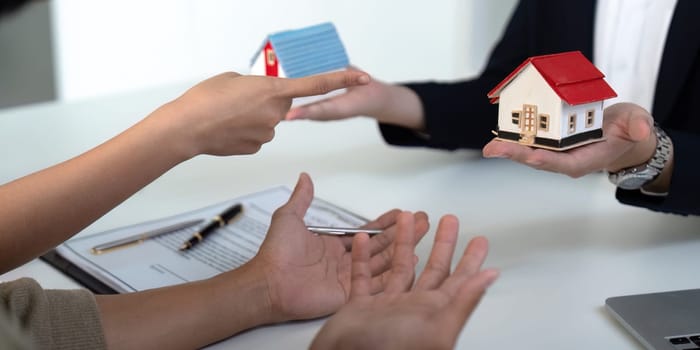 The couple communicates their needs and preferences to a real estate agent, emphasizing teamwork in selecting the right property in a competitive market.