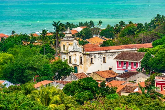 Church and historic buildings of the city of Olinda emerging from the tropical vegetation and the sea.