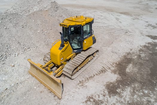 A yellow and black construction vehicle is sitting in a pile of dirt. The vehicle is a bulldozer