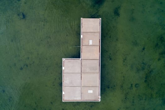 A dock is shown in the water with a view of the sky. The dock is empty and the water is green