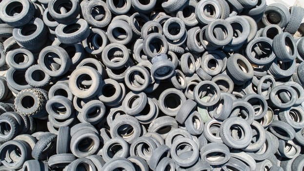 A pile of old tires with a lot of different sizes. The tires are all different colors and sizes, and they are piled on top of each other. Concept of waste and disorganization