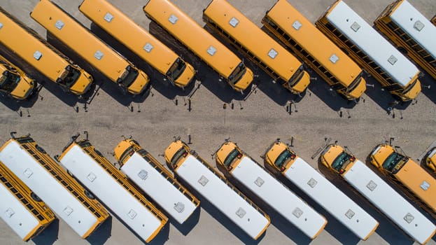 A row of yellow school buses are parked in a lot. The buses are all the same color and are lined up in a row