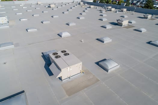 A large building with many vents and a large air conditioner. The vents are all different sizes and are spread out across the roof