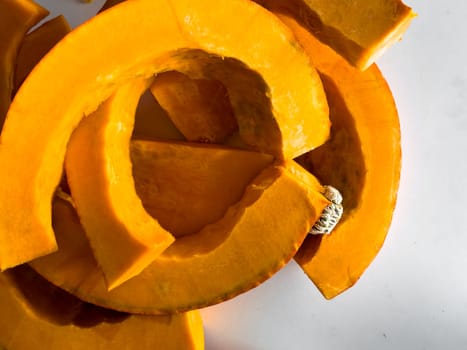 Fresh sliced pumpkin on white background with bright orange color and textured surface.