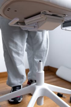 Man assembling office chair base in room with wooden floor.