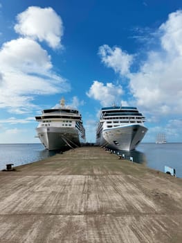 Bermuda, U.S. 10.22.2023 A pair of modern cruise ships are moored at a long concrete pier on a sunny tropical island. The clear blue sky and calm sea create an ideal setting for travel and vacation.