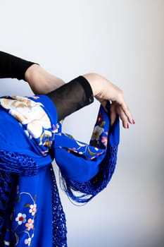 Elegant female hands in blue floral shawl with graceful gesture.