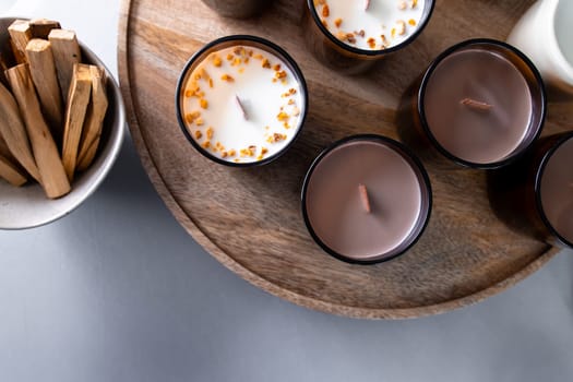 Aromatic scented candles with wooden wicks on round tray.