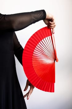 Person holding red fan with black sleeves.