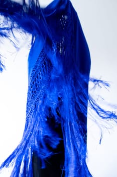 Dynamic blue fabric movement with fringe detail against white background.