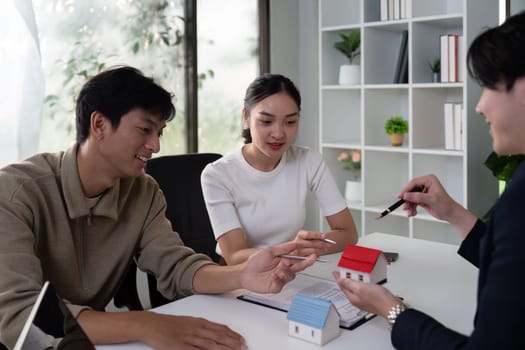 The couple actively discusses property features with their real estate agent, reflecting their preferences and interacting with small models during a consultation.