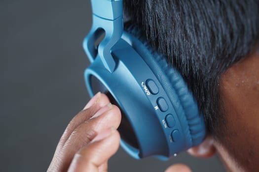 A person is carefully adjusting the volume on blue headphones.