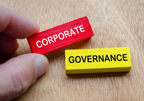 Hand holding Corporate Governance text on colored wooden blocks. Corporate Governance concept