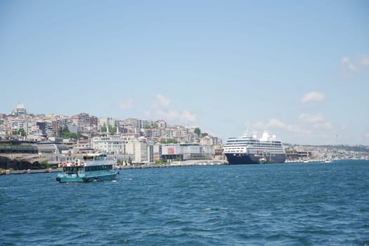 A busy port with a docked cruise ship and small ferry in clear weather.