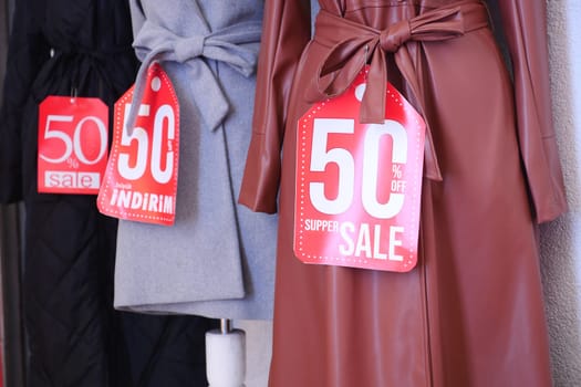 Trendy coats with vibrant sale signs attract shoppers in a boutique.