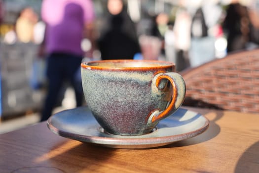 A cozy cup of coffee sits on a saucer, surrounded by a bustling crowd.