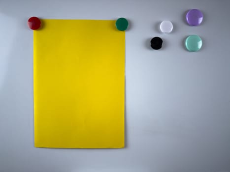 Bright yellow note attached to whiteboard with magnets. Perfect for organizing tasks and reminders in office or classroom setups. Enhancing productivity and communication