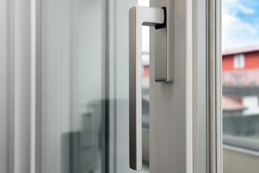 Aluminum window open detail. Metal door frame closeup view. Sound insulation. Energy efficient, safety profile, blur garden outdoor background.