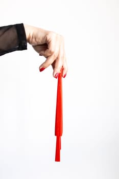 Female hand holding red candle with black sleeve on white background.