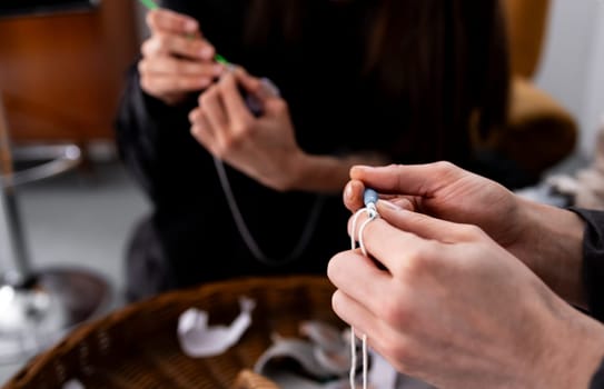 Young caucasian adults knitting with focused hands in a cozy setting.