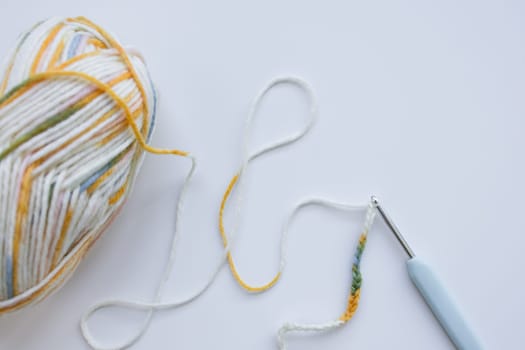Colorful yarn and crochet hook on white background.