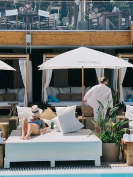 Woman in a straw hat lies on a double sun lounger by the pool. High quality photo