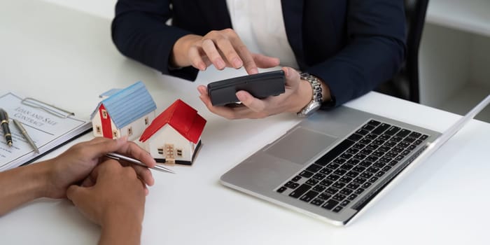 In a detailed property discussion, a real estate agent uses a smartphone to analyze market trends and provide insights to clients considering a home purchase.