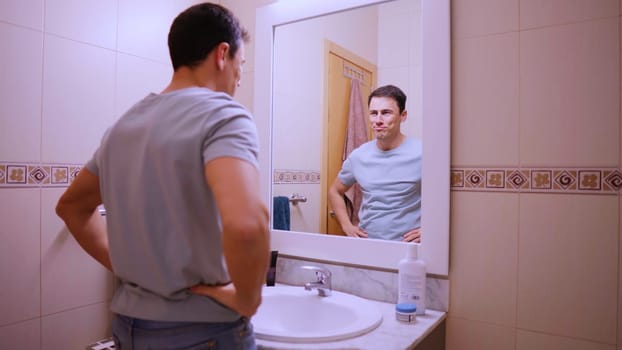 Man looking at his reflection in the bathroom mirror, expressing confidence and optimism for the day ahead