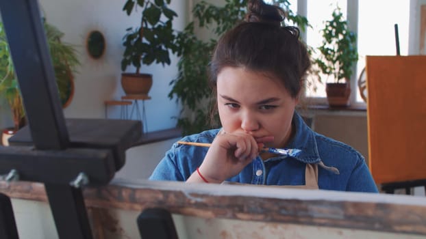 A chubby indpired woman paint artist drawing a painting with a brush. Mid shot