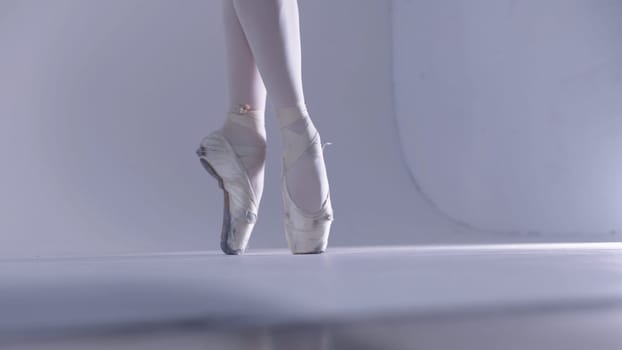 Young woman ballerina walking on pointe shoes. Mid shot