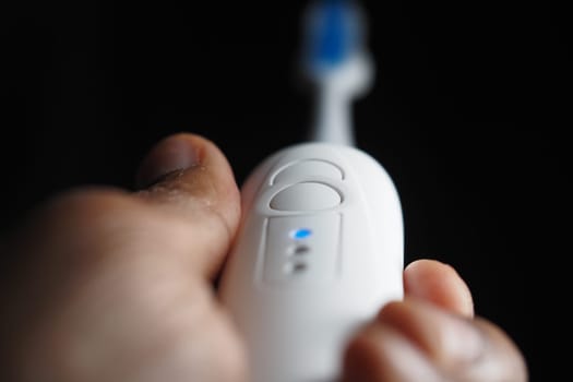 Close-up of a person holding an electric toothbrush for dental hygiene.