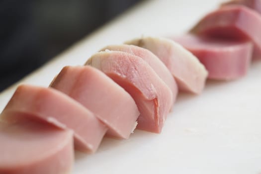 Slices of fresh fish displayed on a cutting board in a kitchen.