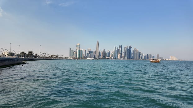 Skyline of a modern city is visible from the water with a boat nearby.
