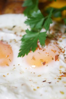 Two perfectly cooked sunny-side up eggs topped with herbs and spices.