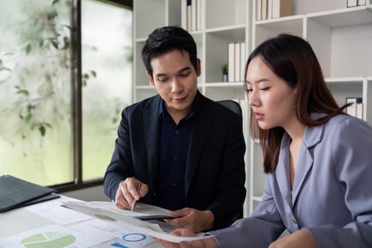 A professional pair reviews analytical reports with charts and graphs, showcasing teamwork in decision-making processes in a modern office atmosphere.