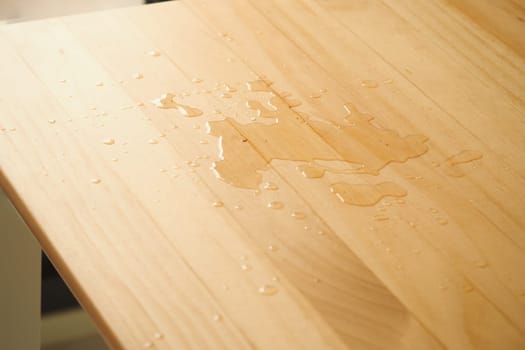 Water spilled on a wooden table surface in natural light.