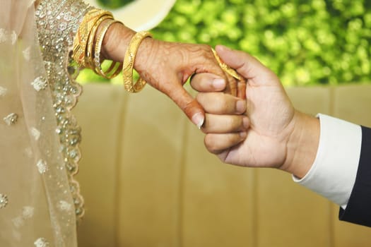 Hands of a bride and groom clasped together, symbolizing unity at dusk.