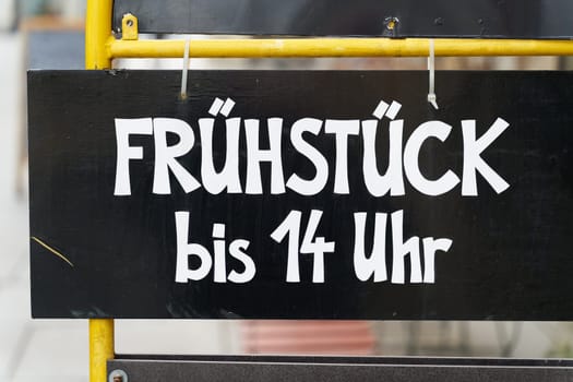 Sign in front of a cafe with the German inscription Frühstück bis 14 Uhr. Translation: Breakfast until 2 pm
