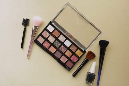 Colorful eyeshadow palette and makeup brushes displayed on a table surface.