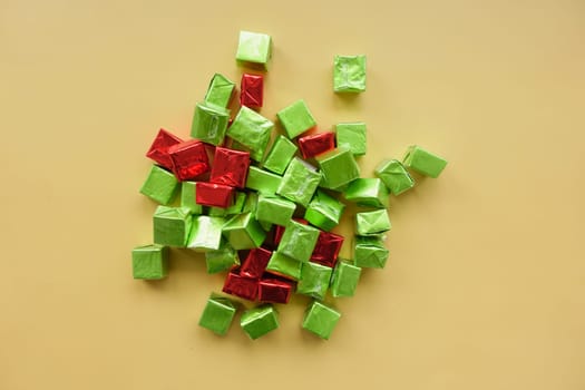 Brightly wrapped candy squares in red and green are scattered on yellow.