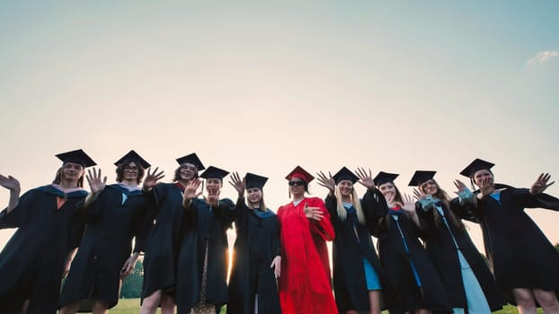 Cheerful graduating students in gowns and mortarboards celebrating their academic achievements together at sunset