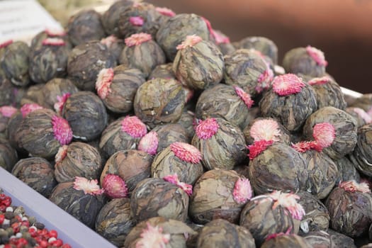 Colorful dried flower tea balls are arranged for sale in a market setting.