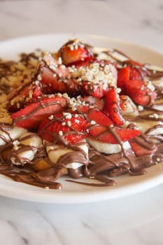 A dessert plate featuring strawberries, bananas, and chocolate drizzle.