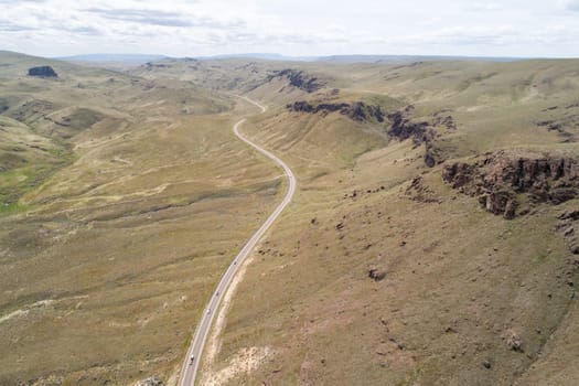 A long road winds through a desert landscape. The road is empty and the sky is clear
