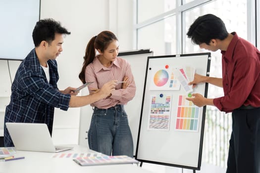 In an inspiring office environment, team members are analyzing vibrant design layouts on a presentation board, sharing insights and feedback on creative ideas.