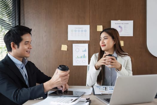 During a coffee break, two coworkers share ideas and laughter over beverages, building rapport and enjoying their collaborative work atmosphere in a modern office.