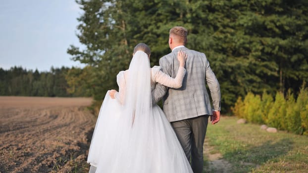 Bride and groom walking away on a path, seen from behind, enjoying their wedding day in a natural setting