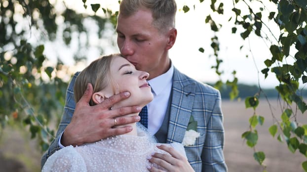 Loving newlyweds embracing near birch tree, capturing intimate wedding moment with gentle togetherness and heartfelt connection