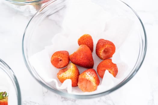 Freshly washed and dried strawberries are carefully arranged in a glass bowl lined with paper towel, ready for snacking or further use.