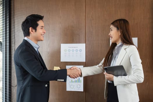 In a bright office, a man and woman shake hands, reflecting a strong professional relationship built on mutual respect and shared goals.